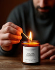 Person lighting a candle labeled 'Golden Mandarin' with a blurred background