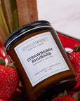 Sparkle Candle Strawberry Rhubarb candle with strawberries and rhubarb stalks on a red plate.