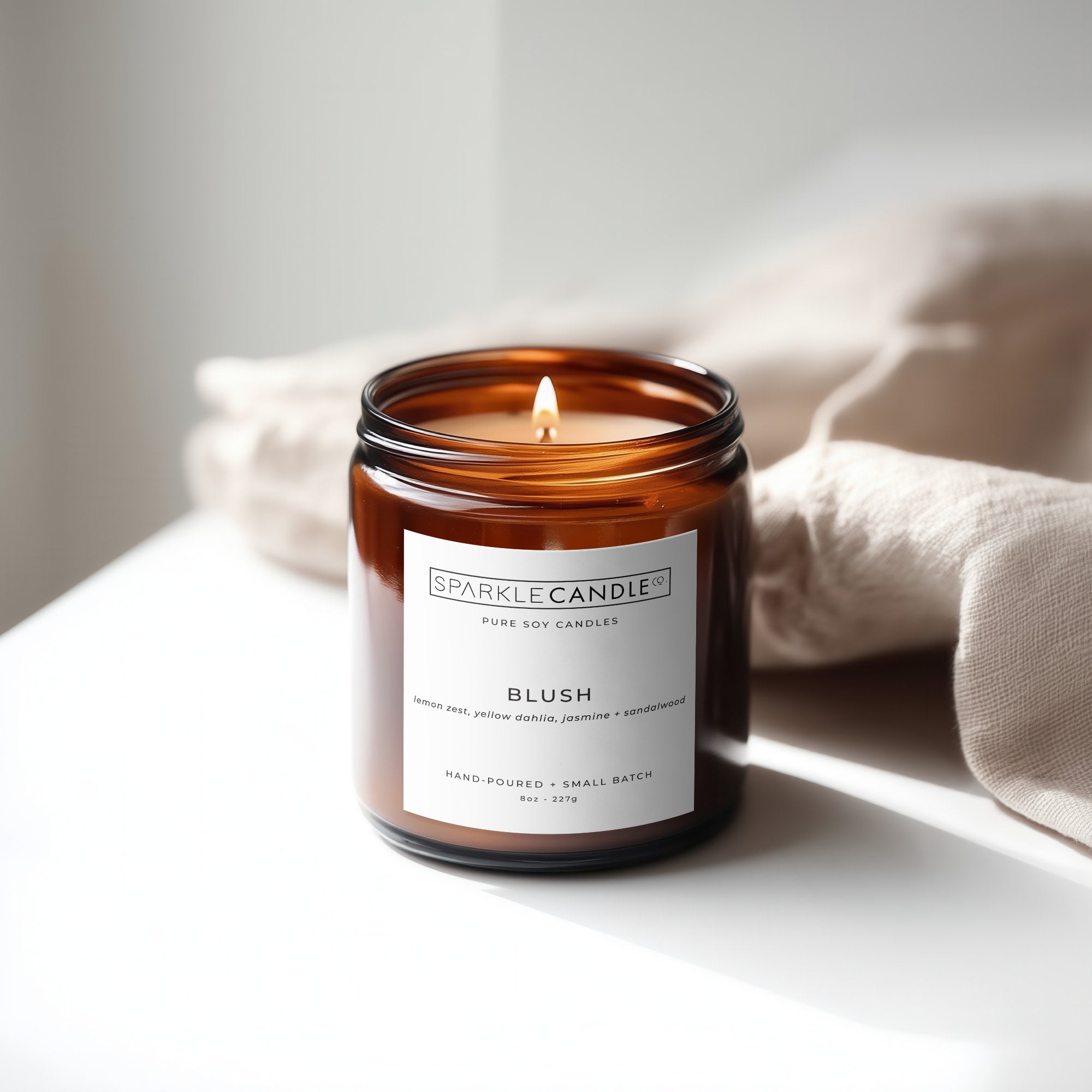 Sparkle Candle Blush soy candle in an amber jar on a light surface with a neutral background