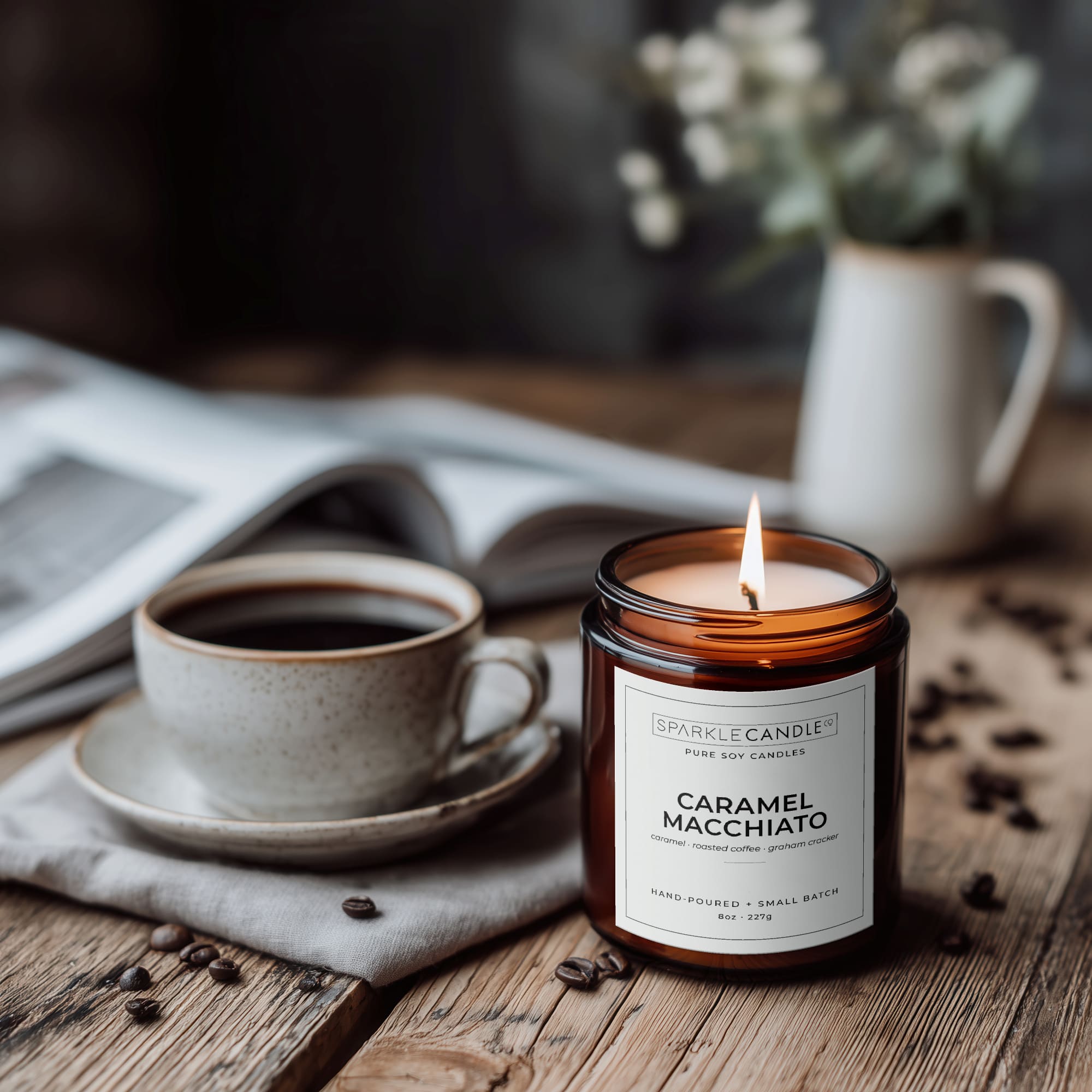 Candle labeled 'Caramel Macchiato' next to a cup of coffee on a wooden table.