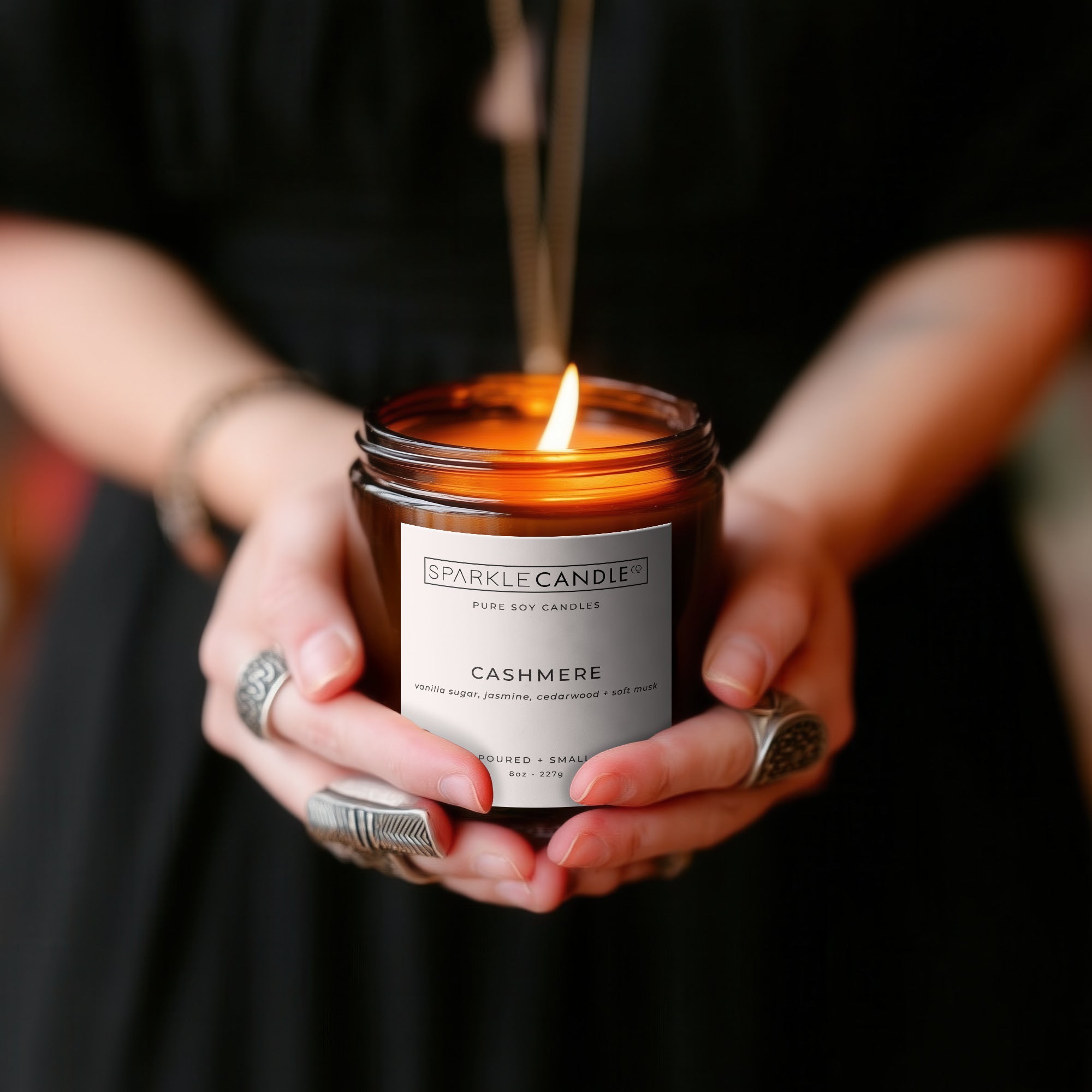 Cashmere soy candle styled in ladies hands with a black dress and silver rings