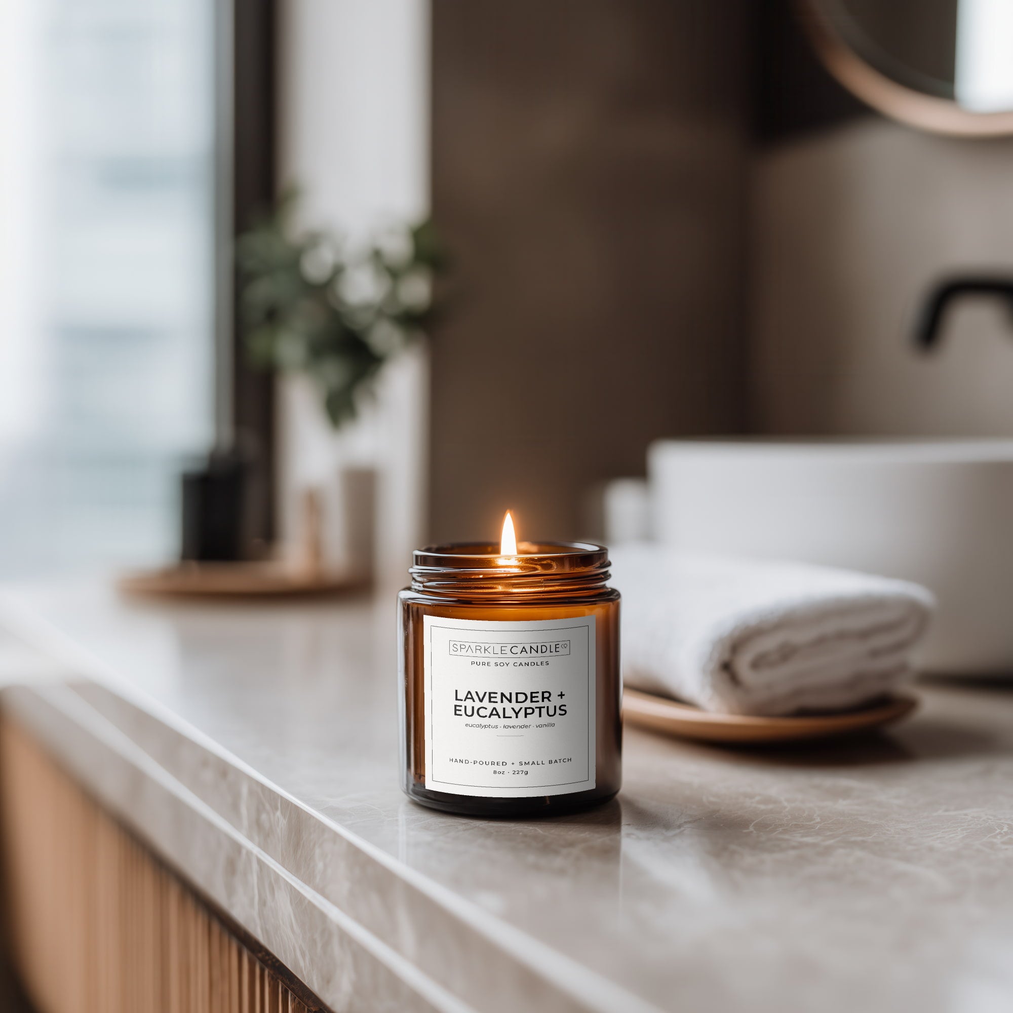 Candle labeled 'Lavender + Eucalyptus' on a marble surface with a blurred background