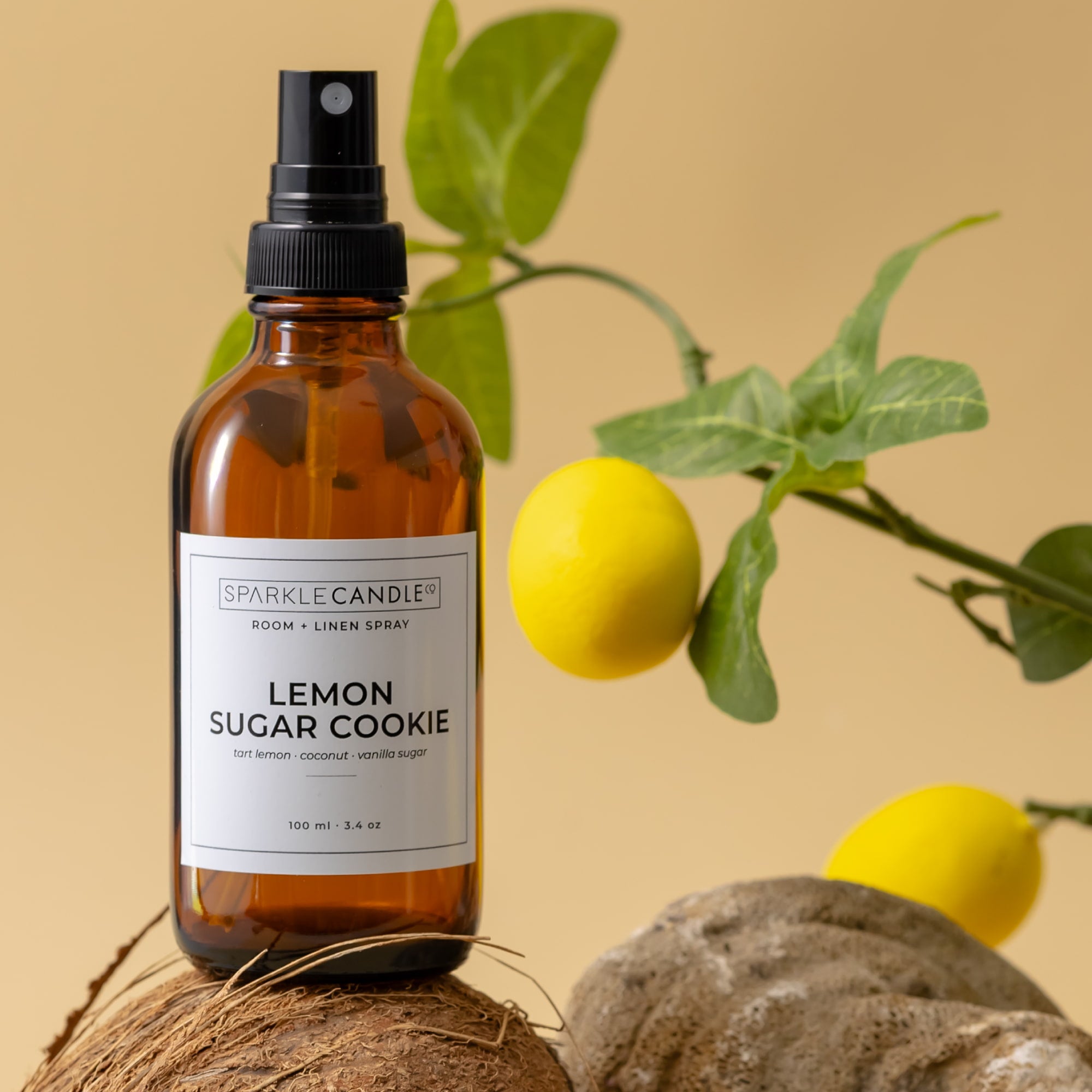 Bottle of 'Lemon Sugar Cookie' room spray with lemons and coconut on a beige background