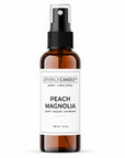 Brown spray bottle with a white label for peach magnolia room spray on a white background