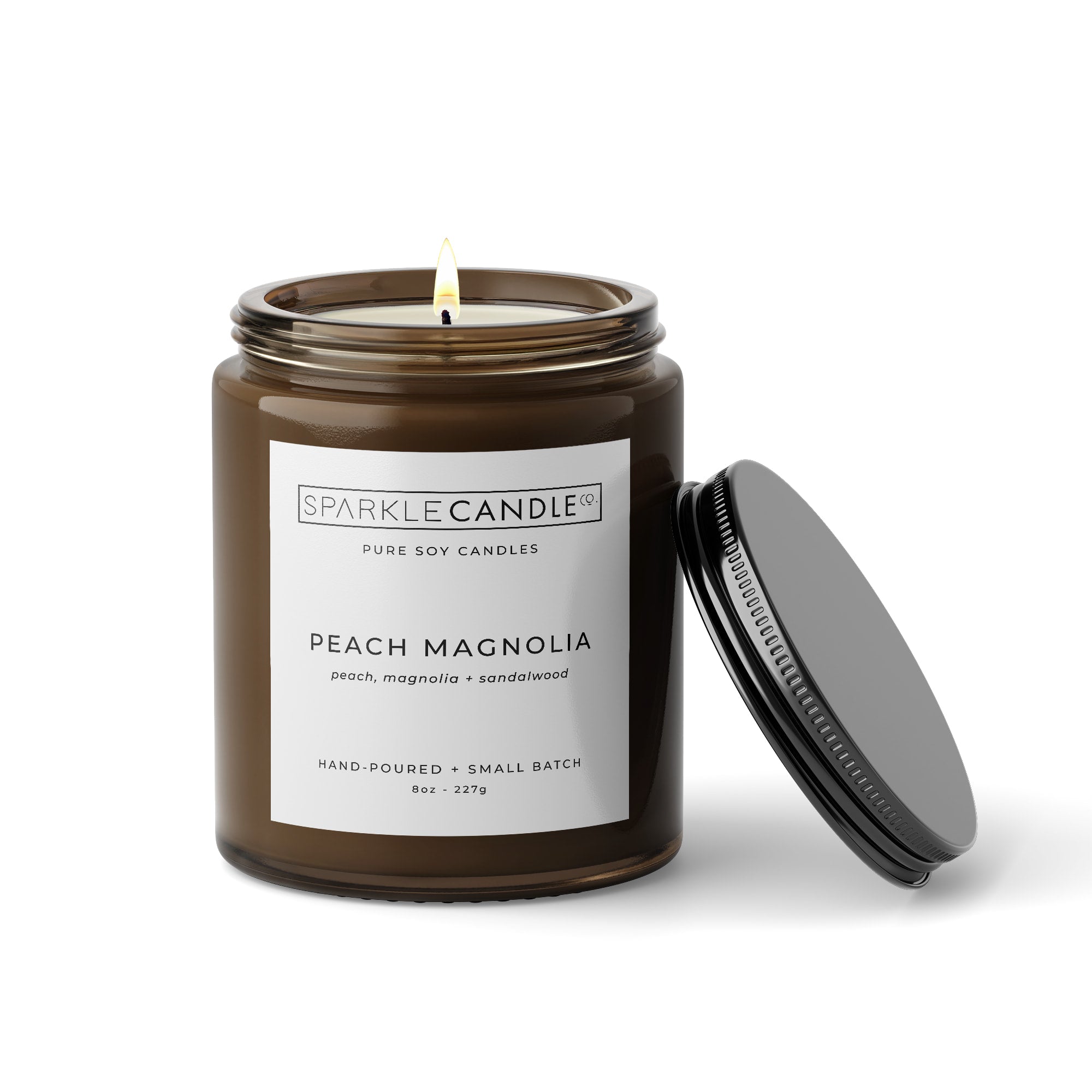 Peach Magnolia soy candle in an amber jar with a black lid on a white background