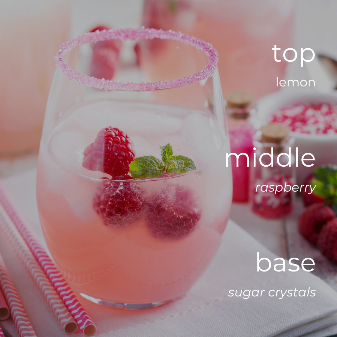 Pink lemonade with raspberries and sugar crystals on a white surface