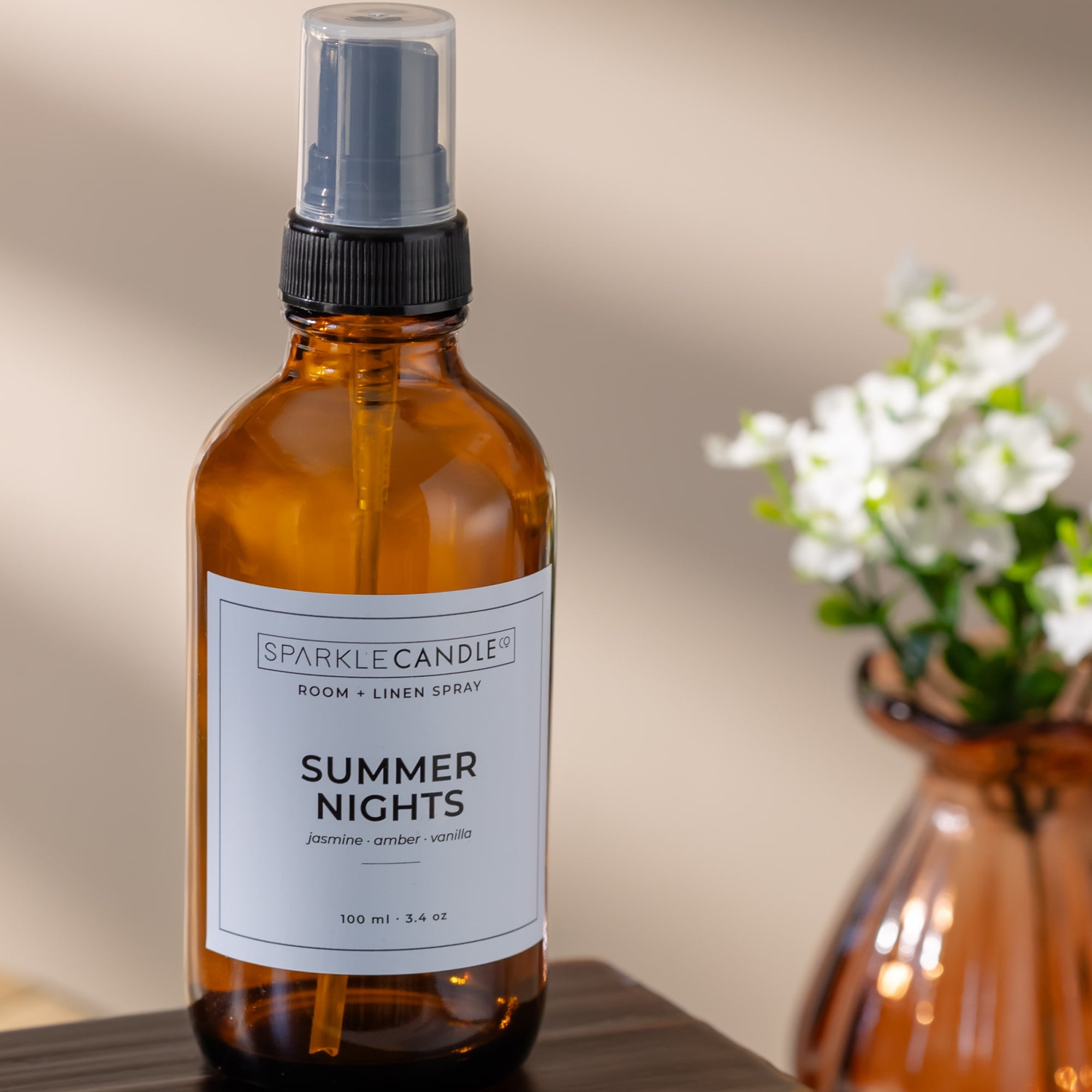 Summer nights room and linen spray on a wood surface with a amber vase and flower behind