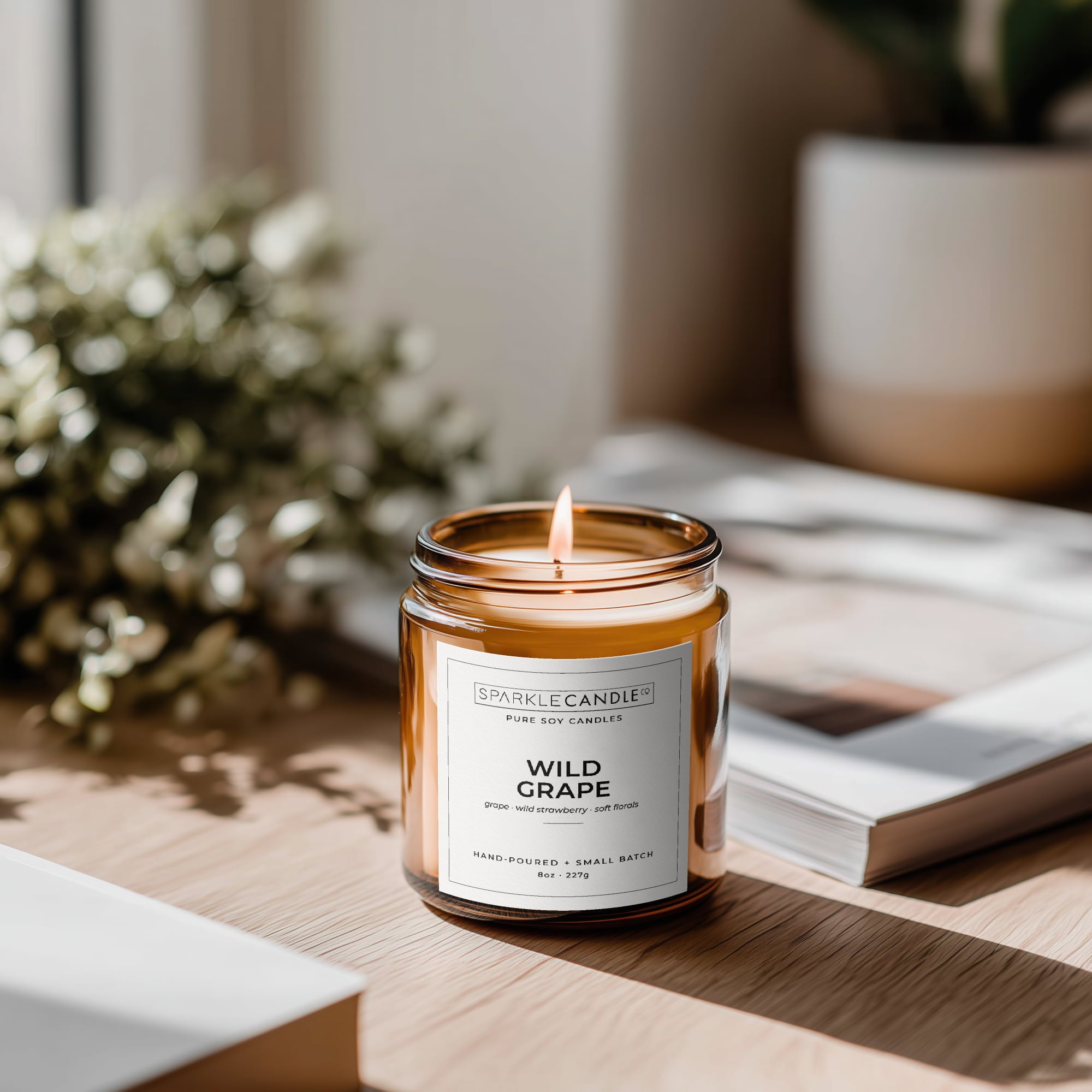 Candle labeled 'Wild Grape' on a wooden surface with a blurred background